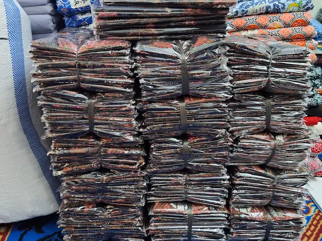 Tumpukan paket pesanan seragam batik custom siap kirim dalam jumlah besar dari pabrik